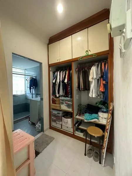 Laundry features: built-in wardrobe with sliding doors, hanging clothes rack, plastic storage boxes, white tiled flooring, light fixture on ceiling, small stool, slippers on floor, grey area rug.