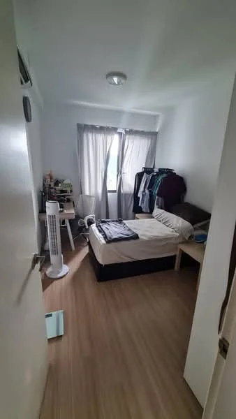 Bedroom features: queen-size bed, wooden bed frame, light wood flooring, white painted walls, floor-to-ceiling window, sheer curtains, nightstand, table lamp, clothes rack, standing fan.