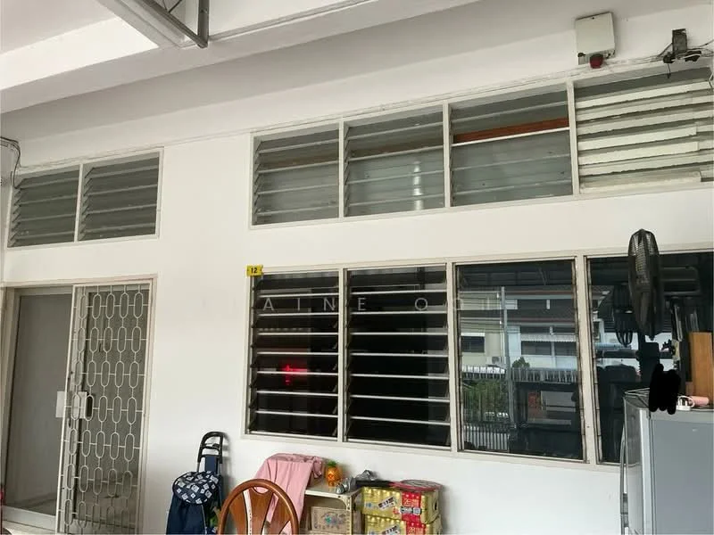 Room features: white painted walls, sliding windows, grilled security door, wooden dining table, plastic chair, storage cabinet, pink fabric, visible outdoor view.