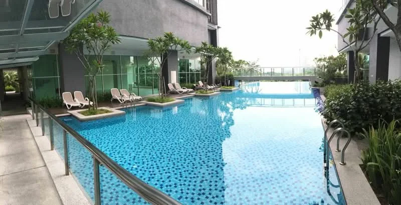 Exterior type: swimming pool deck; features: infinity pool, pool deck with loungers, tropical landscaping, manicured greenery, glass railing, paved walkway, water feature, surrounding palm trees; style: modern.