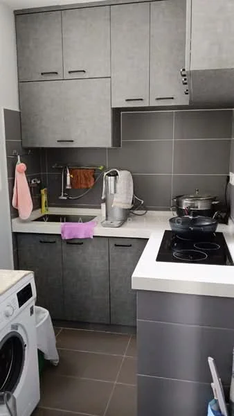 Kitchen features: grey cabinetry, white countertop, stainless-steel sink, chrome pull-down faucet, built-in induction cooktop, wall-mounted range hood, ceramic tile backsplash, washing machine, kitchen towels, cooking pot, kitchen utensils, dark tiled flooring; style: modern.