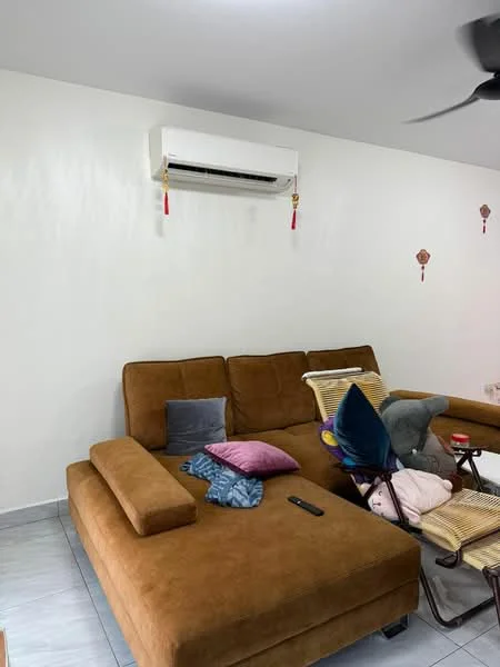 Living features: brown fabric sectional sofa, decorative cushions in various colors, wall-mounted split air conditioning unit, light-colored painted walls, grey tiled flooring, small coffee table, remote control on the floor, decorative wall hangings; style: modern.