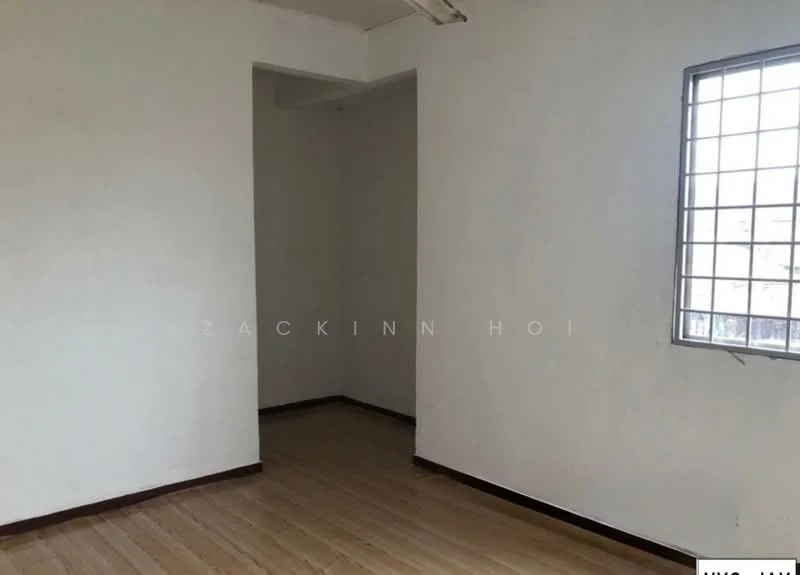 Room features: white painted walls, wooden flooring, single window with metal grille, corner room layout, no visible furniture, plain ceiling, light fixture on ceiling; style: minimalist.