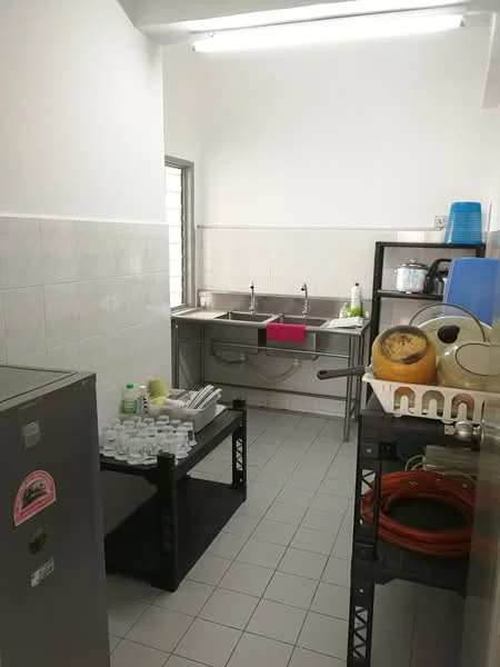 Kitchen features: double-bowl stainless-steel sink, chrome pull-down faucet, white tiled walls, grey tiled flooring, stainless-steel countertop, metal shelving unit, refrigerator, dish rack, cleaning supplies, plastic containers, window with metal grille, overhead fluorescent lighting; style: functional.