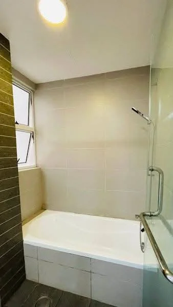 Bathroom features: bathtub, shower with glass enclosure, chrome handheld showerhead, tile cladding on walls, grey tiled flooring, window for natural light, grab bar, light fixture on ceiling; style: modern.