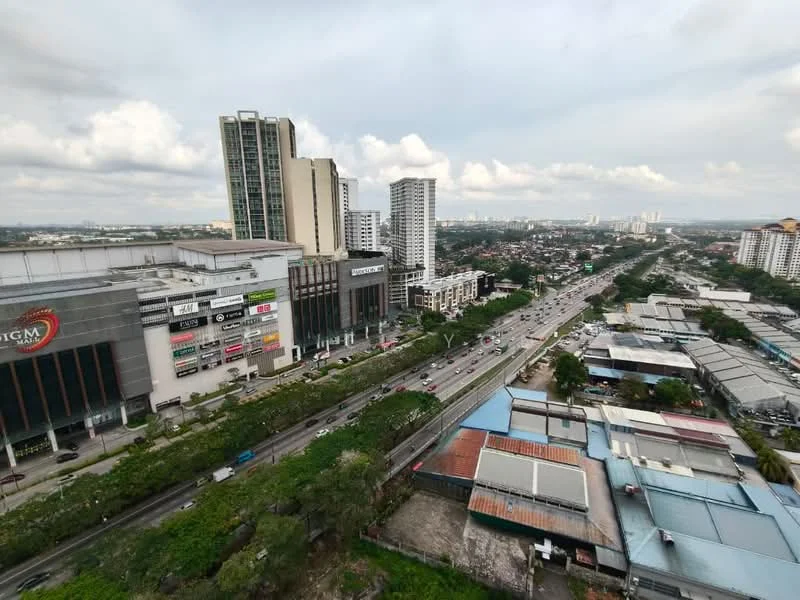 Exterior type: high-rise condominium; features: city skyline view, surrounded by urban landscape, nearby shopping mall, multiple high-rise buildings, main road visible, greenery along the road; style: modern.