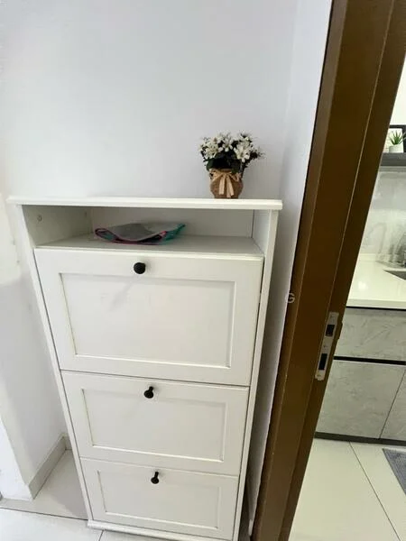 Room features: white storage cabinet with three drawers, decorative flower pot, white walls, tile flooring; style: modern.