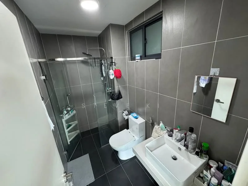 Bathroom features: grey tiled walls, black tiled flooring, walk-in shower with glass enclosure, rain shower head, handheld shower, single-sink vanity with white cabinet, chrome basin mixer faucet, one-piece toilet, framed mirror, window for natural light, various toiletries on countertop, towel rack; style: modern.