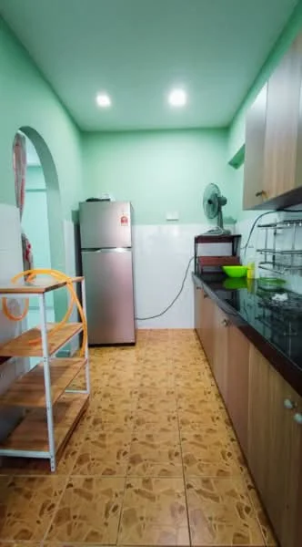 Kitchen features: green painted walls, ceramic tile flooring, stainless-steel fridge, black granite countertop, wood cabinetry, wall-mounted fan, open shelving unit, sink, overhead lighting.