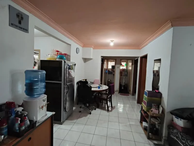 Room features: white painted walls, cream ceiling with crown moulding, white tiled flooring, water dispenser, black office chair, round dining table, wooden dining chairs, refrigerator, kitchen cabinets, doorway leading to other rooms, wall clock, storage boxes, open space layout; style: modern.
