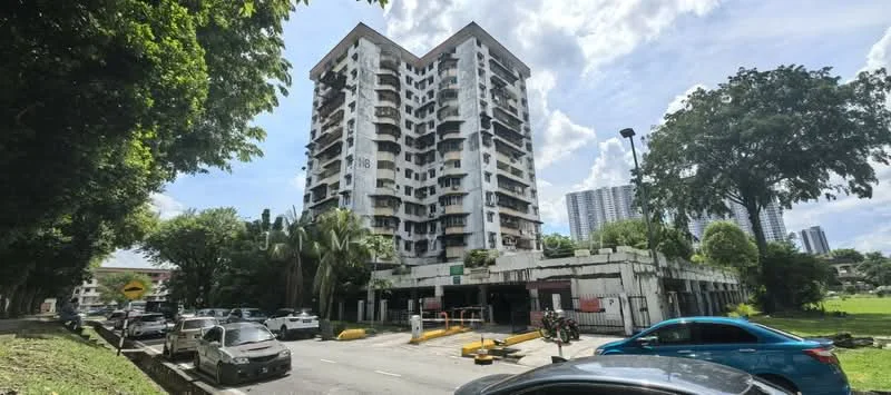 Exterior type: mid-rise condominium; features: white painted facade, balconies with railings, parking area at ground level, surrounded by greenery, multiple storeys, entrance with security gate, landscaped surroundings, nearby road access; style: modern.