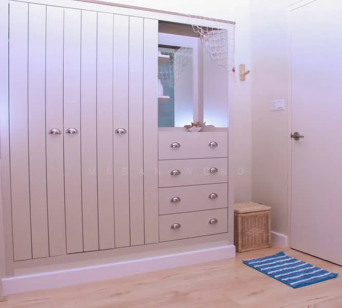 Room features: built-in wardrobe with vertical paneling, light beige cabinetry, six cabinet doors, five drawers, metal handles, woven storage basket, blue striped area rug, light-colored wall, door leading to another room; style: modern.