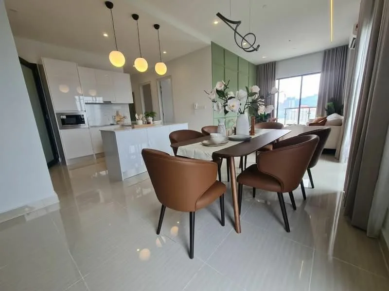Dining features: 6-seater dining table, brown leather dining chairs, pendant lighting with three globes, large window with city view, white cabinetry, kitchen island, marble countertop, polished tile flooring, decorative vase with flowers, neutral wall color, green accent wall, sofa in background; style: modern; view: city. Kitchen features: white cabinetry, built-in oven, microwave, stainless-steel appliances, kitchen island, marble countertop, open-plan layout; style: modern; view: city.
