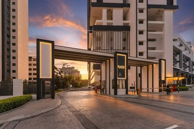 Exterior type: high-rise condominium; features: modern facade with glass and concrete, feature lighting at entrance, gated entry with guard house, paved driveway, landscaped greenery, surrounded by mature trees, double-volume main lobby, parking area visible; style: modern.