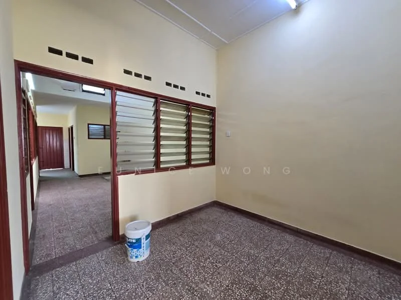 Room features: cream painted walls, tile flooring, sliding windows with metal grilles, ceiling lights, doorway leading to another room, doorway with wooden door, baseboard, bucket on the floor.