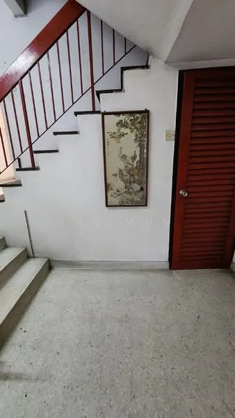 Room features: white painted walls, concrete flooring, red metal railing, staircase, framed artwork on wall, wooden door with slats; style: minimalist.