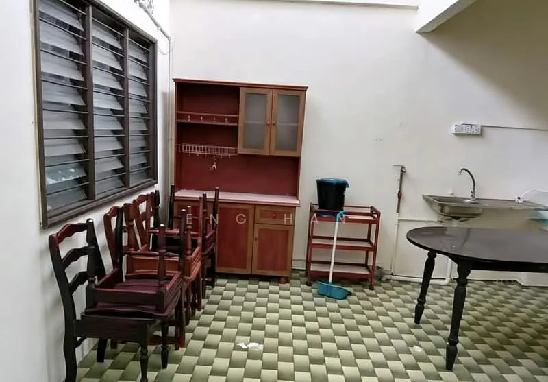 Room features: green and cream checkered tile flooring, white painted walls, wooden cabinet with glass doors, wooden dining table, four wooden chairs, metal sink, cleaning broom, wooden cart, window with horizontal slats.