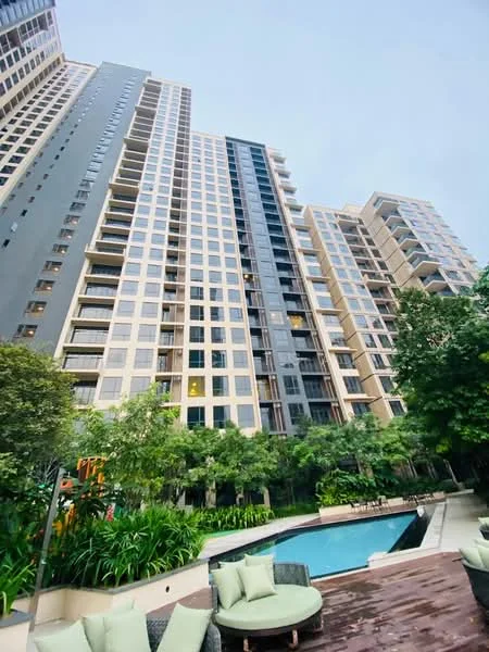 Exterior type: high-rise condominium; features: glass curtain wall, cream painted facade, recessed balconies, manicured lawn, mature trees, swimming pool, pool deck with loungers, surrounded by greenery; style: modern.