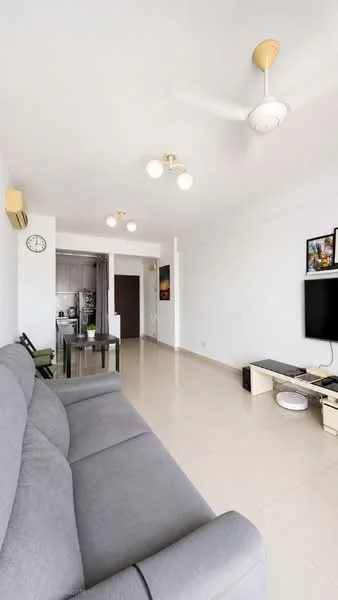 Living features: grey fabric sofa, coffee table, wall-mounted TV, TV console, 5-blade ceiling fan with light, recessed downlights, cream tiled flooring, white painted walls, clock on wall, open layout to kitchen, air conditioning unit; style: modern.