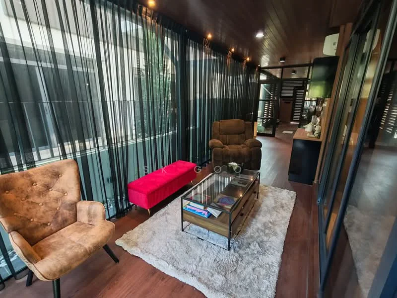 Living features: two armchairs in beige fabric, red upholstered bench, glass coffee table with wooden frame, area rug with plush texture, wooden flooring, recessed ceiling lights, floor-to-ceiling windows, sheer black curtains, decorative wall art, wall-mounted TV, greenery visible outside; style: modern; view: garden.