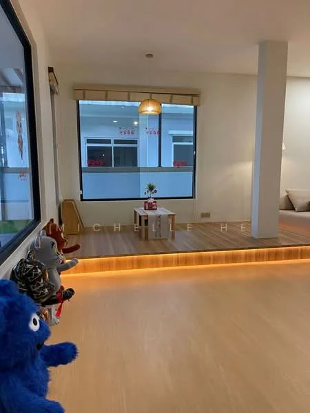 Room features: large window with natural light, wooden flooring, neutral wall color, decorative pendant light, small table with flower vase, seating area with cushions, plush toys on display, minimalist decor; style: modern.