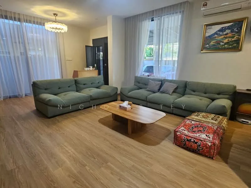 Living features: 3-seater fabric sofa in green, coffee table with wooden surface, area rug with geometric pattern, floor-to-ceiling windows with sheer curtains, wall-mounted air conditioning unit, decorative painting on wall, wooden flooring, light fixture with chandelier design; style: modern.