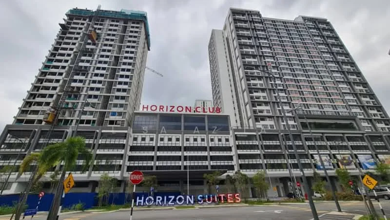 Exterior type: high-rise condominium; features: glass curtain wall, white painted facade, projecting balconies, signage with 'HORIZON CLUB' and 'HORIZON SUITES', multiple storeys, surrounded by landscaped greenery, pedestrian pathways, urban context with nearby roads; style: modern.