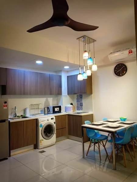 Kitchen features: brown wooden cabinetry, white countertop, stainless-steel fridge, built-in microwave, freestanding washing machine, 4-blade ceiling fan with light, pendant lighting with colored shades, ceramic tile flooring, wall-mounted split AC, blue dining chairs, 4-seater dining table, decorative wall tiles with pattern, clock on wall; style: modern.