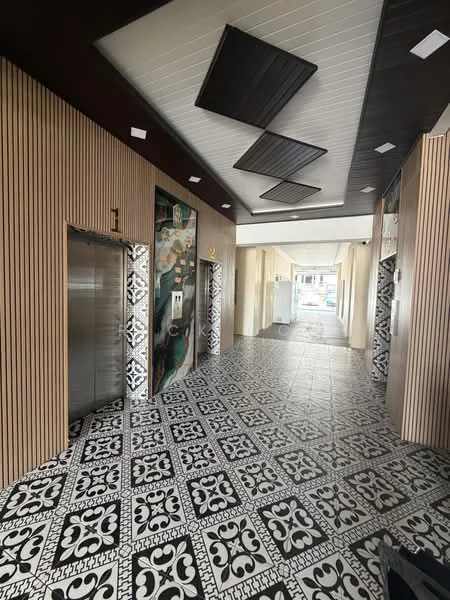 Room features: elevator doors, decorative wall art, black and white patterned floor tiles, wood paneling on walls, recessed ceiling lights, ceiling with geometric design, light-colored walls, open corridor layout; style: modern.