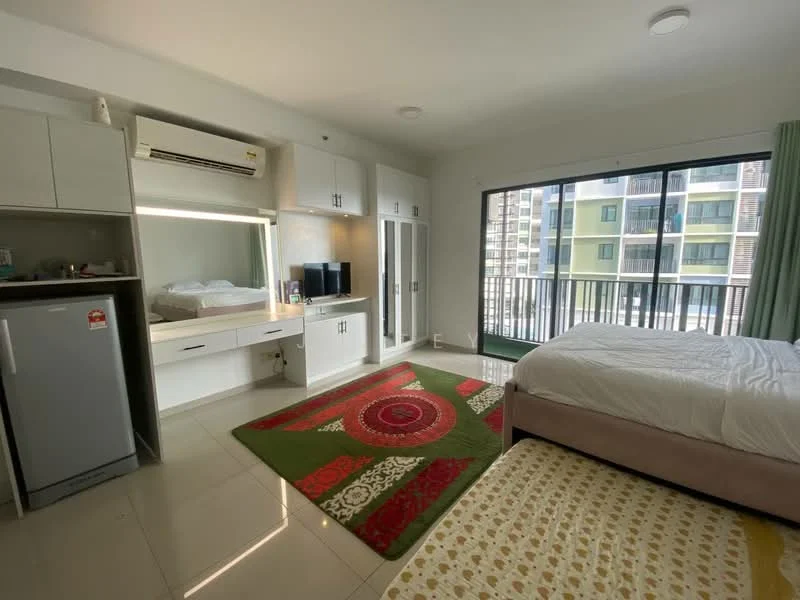 Bedroom features: queen-size bed with upholstered headboard, white bedding, 2 bedside lamps, built-in wardrobe with sliding doors, study desk with mirror, TV console, refrigerator, floor-to-ceiling windows, green curtains, area rug with geometric pattern, wall-mounted air conditioning unit, white painted walls, glossy tile flooring; style: modern.