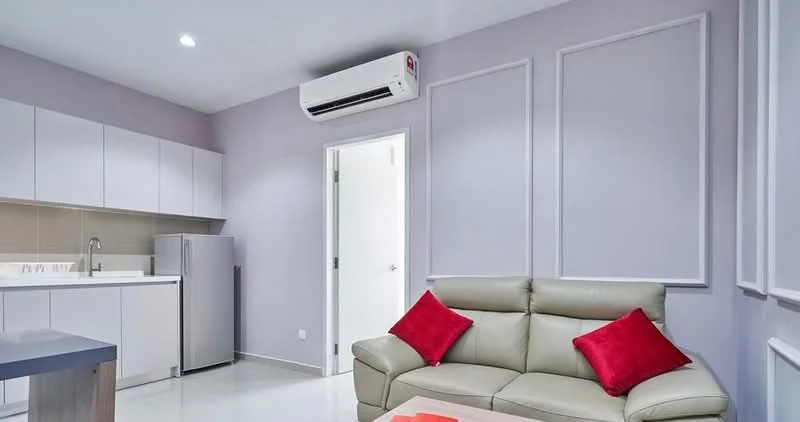 Living features: light grey painted walls, white cabinetry, stainless-steel fridge, single-bowl stainless-steel sink, white countertop, 2-seater leather sofa in beige, red accent cushions, recessed downlights, wall-mounted split AC, white door, floor tiles, decorative wall panels; style: modern.