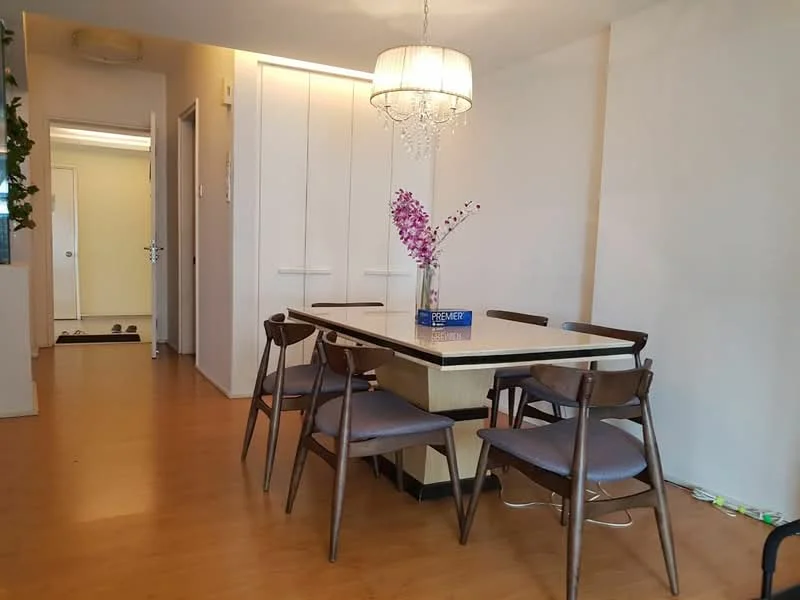 Dining features: wooden dining table, 6-seater dining table, upholstered dining chairs, chandelier light fixture, decorative vase with flowers, laminate flooring, white painted walls, built-in cabinets; style: modern. Hallway features: white painted walls, laminate flooring, doorway leading to other rooms.