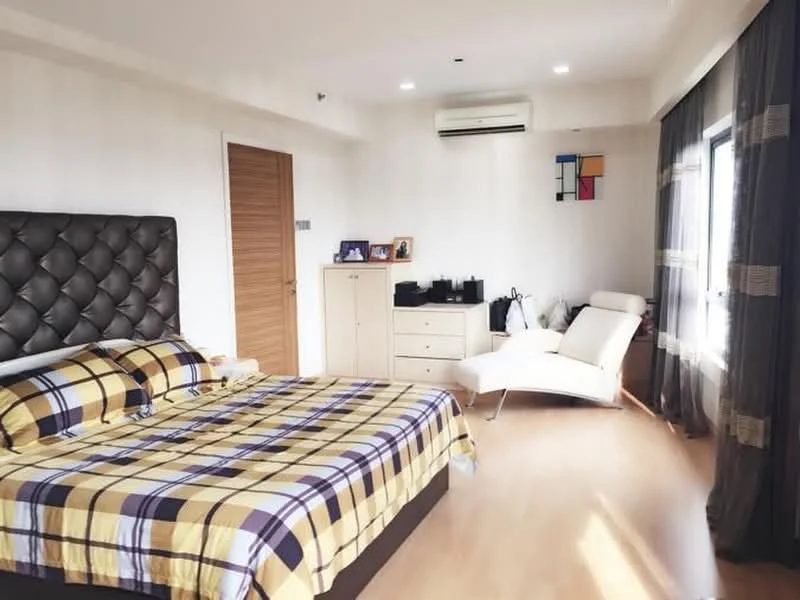 Bedroom features: king-size bed with upholstered headboard, plaid bedding in yellow and brown, wooden flooring, floor-to-ceiling window, sheer curtains, recessed downlights, 1 wall-mounted split AC, white armchair, chest of drawers, decorative wall art; style: modern.