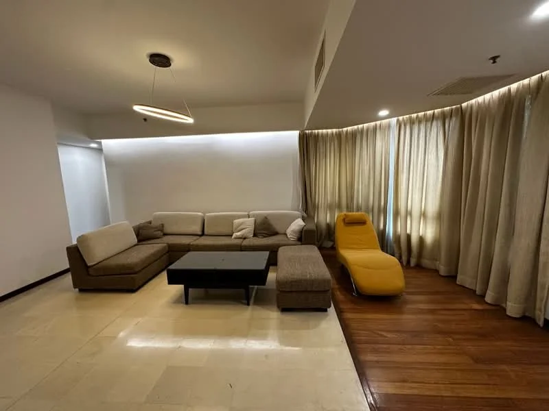 Living features: L-shape sectional sofa in beige, coffee table, area rug, floor-to-ceiling windows, sheer curtains, recessed downlights, wood flooring, cream painted walls, ceiling light fixture, decorative wall paneling; style: modern.