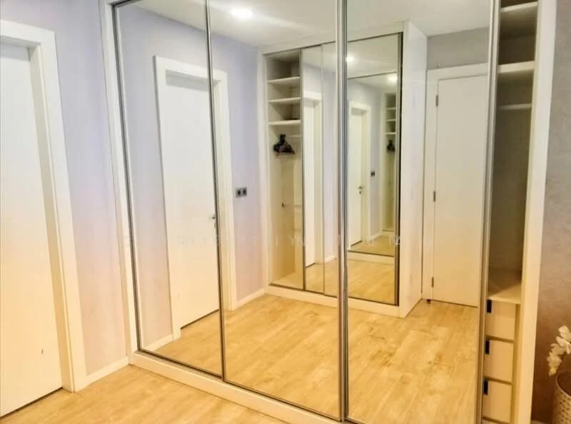 Room features: mirrored sliding wardrobe, light wood flooring, white painted walls, built-in shelving, white door, neutral wall color, recessed lighting; style: modern.