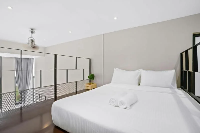 Bedroom features: king-size bed with white bedding, two white towels rolled on the bed, grey painted walls, wooden flooring, ceiling fan with light, floor-to-ceiling windows, sheer curtains, decorative plant on bedside table, metal railing, recessed downlights; style: modern.
