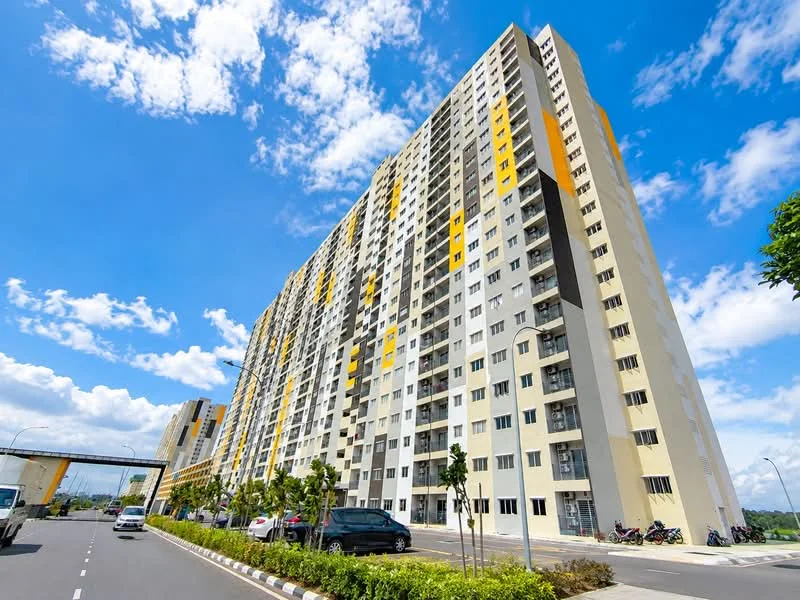 Exterior type: high-rise condominium; features: yellow and grey painted facade, glass windows, multiple storeys, balconies on upper floors, landscaped garden in front, paved walkway, surrounded by greenery, urban context with road access; style: modern.