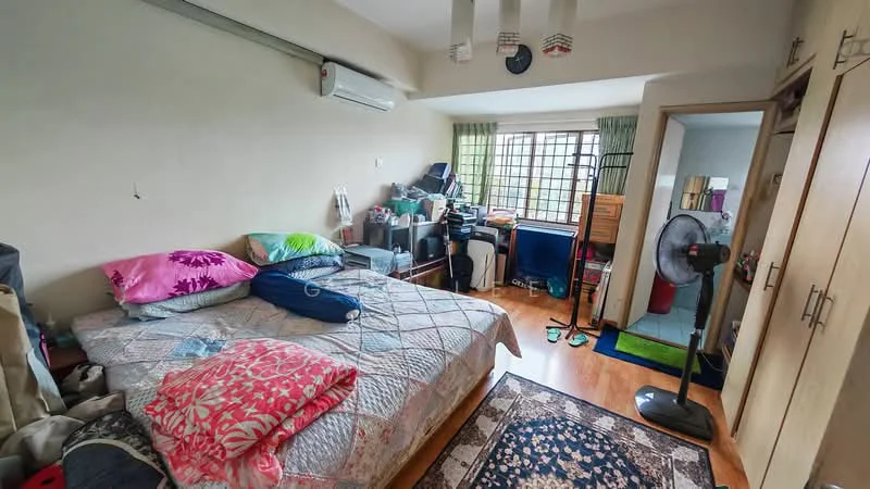 Bedroom features: queen-size bed with patterned bedding, wooden flooring, 1 wall-mounted split AC, green curtains, built-in wardrobe with sliding doors, study desk with chair, floor fan, area rug with floral pattern, decorative pillows, bookshelf, cluttered workspace, mirror on wall.