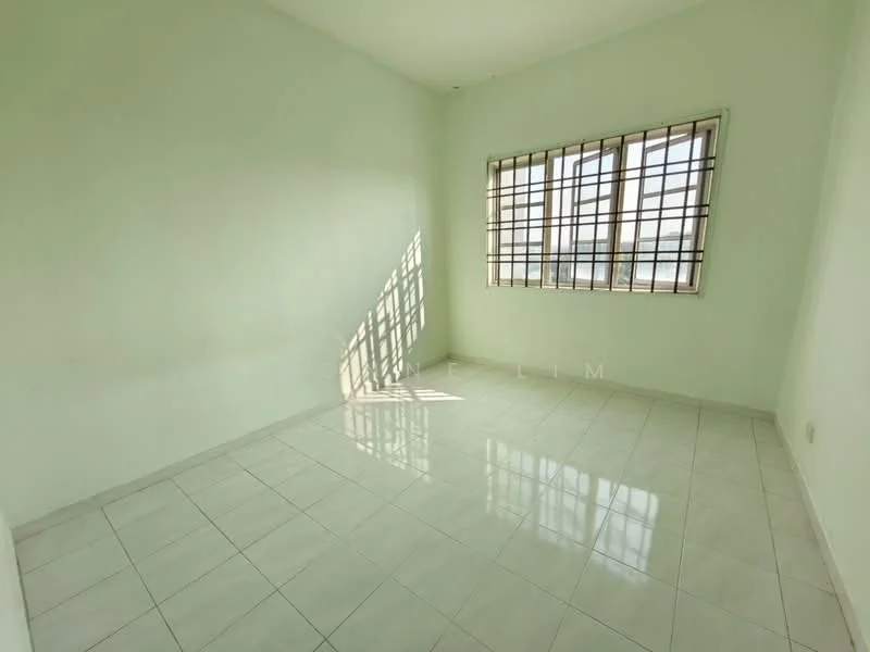 Room features: light green painted walls, white tiled flooring, grill window with multiple panes, natural light from window, no visible furniture, empty space, smooth ceiling, corner of the room with shadows.