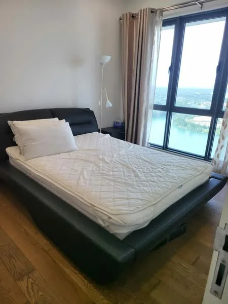 Bedroom features: black leather bed frame, queen-size mattress, wooden flooring, floor-to-ceiling windows, curtains, lamp, view of water, decorative pillows; style: modern; view: water.