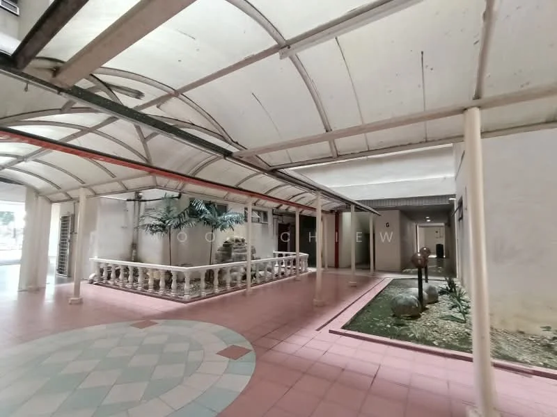 Exterior type: low-rise apartment block; features: covered walkway, decorative railing, paved flooring with geometric pattern, landscaped area with plants, exposed concrete walls, glass roof, potted plants, light fixtures, column supports; style: modern.