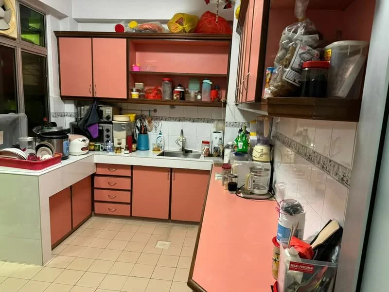 Kitchen features: pink cabinetry, white countertops, double-bowl stainless-steel sink, chrome pull-down faucet, built-in oven, microwave, toaster, blender, rice cooker, various jars and containers on shelves, tile backsplash, ceramic tile flooring, wall-mounted shelves, kitchen appliances visible on countertop.