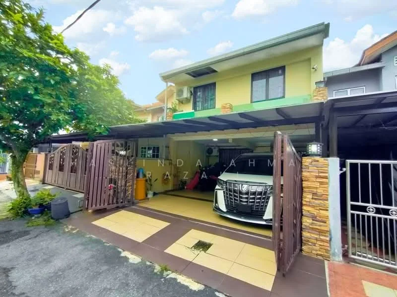 Exterior type: linked terrace house; features: car porch with awning, stone cladding on facade, green painted walls, flat roof, manicured lawn, paved driveway, fence with gate, outdoor lighting, surrounded by greenery; style: modern.