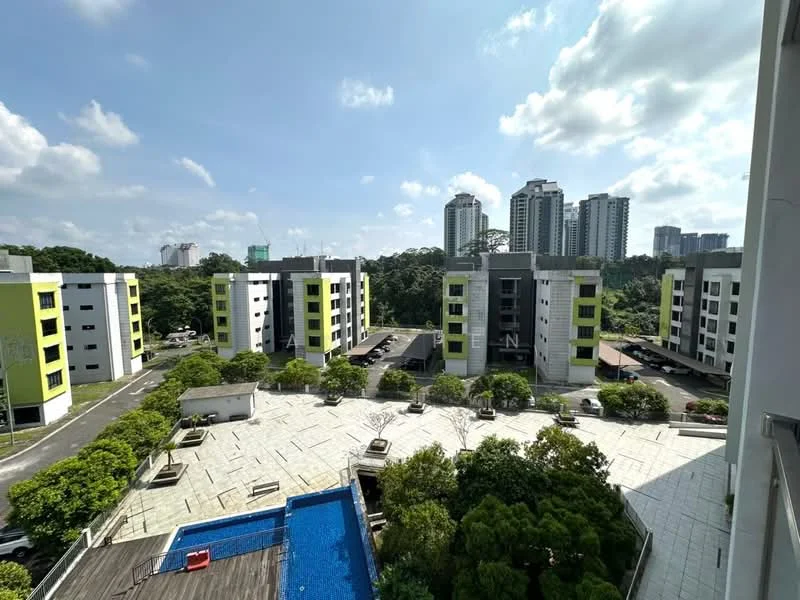 Exterior type: low-rise apartment block; features: green accent facade, concrete structure, landscaped garden, swimming pool, outdoor seating area, manicured lawn, surrounding greenery, parking spaces, multiple low-rise buildings, city skyline in background; style: modern.