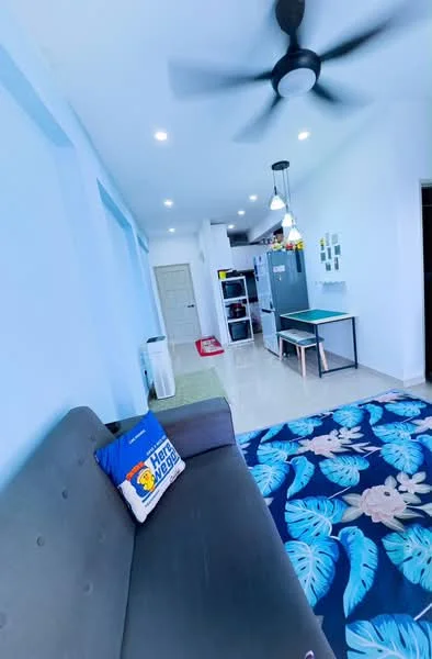 Living features: grey fabric sofa, decorative throw pillow, area rug with floral pattern, ceiling fan, recessed downlights, white painted walls, glossy tile flooring, dining table, kitchenette in background, open layout; style: modern.