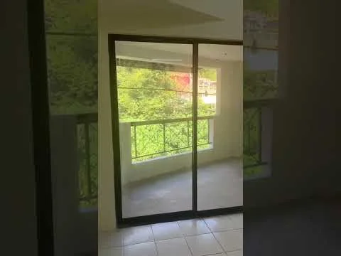 Room features: sliding glass door, floor-to-ceiling windows, white walls, tile flooring, balcony view of greenery; view: garden.