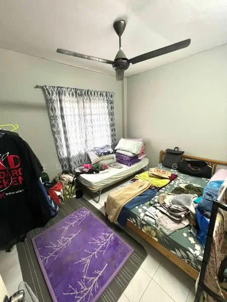 Bedroom features: light grey painted walls, white ceiling, 5-blade ceiling fan, window with sheer curtains, double bed with floral bedding, single mattress on the floor, purple area rug with floral pattern, wooden bed frame, clothes on the floor, clothes hanging on a rack.