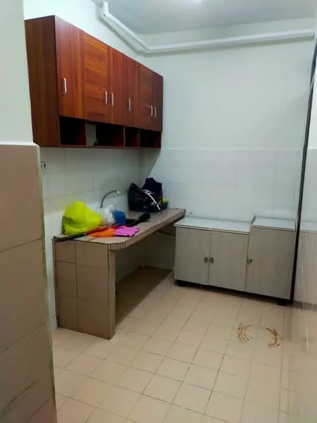 Laundry features: brown wooden upper cabinets, white tiled walls, light beige tiled flooring, sink with chrome faucet, countertop with storage underneath, built-in lower cabinets, various colored cleaning supplies, open space for appliances.