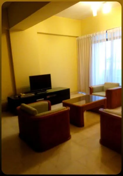 Living features: cream painted walls, marble flooring, ceiling fan, large window with sheer curtains, black TV console, wall-mounted TV, coffee table, 4 armchairs with wooden frames.
