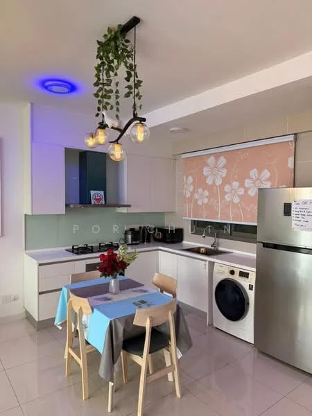 Kitchen features: white cabinetry, grey backsplash, black countertop, stainless-steel fridge, built-in gas hob, built-in oven, front-load washing machine, 4-seater dining table, pendant lighting with bulbs, decorative plant hanging from ceiling, window with floral-patterned roller blind, ceramic tile flooring, recessed ceiling lights; style: modern.